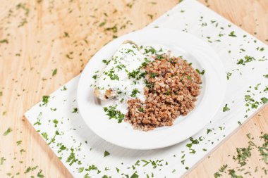 karabuğday balık sosu hafif ahşap arka plan üzerinde beyaz kesme tahtası üzerinde beyaz bir tabakta altında otlar ile serpilir