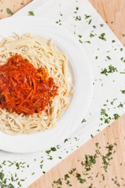 Et ve otlar ile serpilir hafif ahşap arka plan üzerinde beyaz kesme tahtası üzerinde beyaz bir tabakta sos spagetti