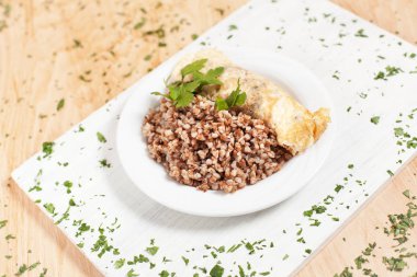 buğday ile ışık ahşap arka plan üzerinde beyaz kesme tahtası üzerinde beyaz bir plaka üzerinde balık otlar ile serpilir