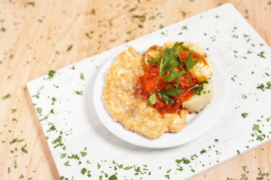 hamuru patates ve beyaz kesme tahtası hafif ahşap arka plan üzerinde beyaz bir tabağa sosu ile Chop pirzola otlar ile serpilir