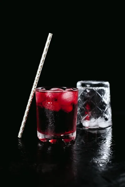 Due bicchieri con un cocktail rosso con ghiaccio su sfondo nero bagnato — Foto Stock