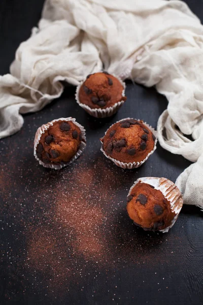 Κέικ σοκολάτας, πασπαλισμένο με κακάο και ζάχαρη και με μια πετσέτα σε σκούρο φόντο ξύλινη — Φωτογραφία Αρχείου