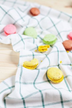 Damalı yeşil havlu üzerinde hafif bir ahşap arka plan üzerinde renkli macaroons