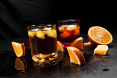 ıslak koyu arka plan üzerinde turuncu ile buzlu kokteyller ile iki bardak