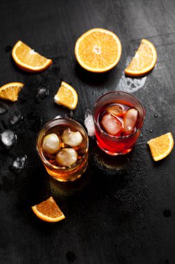 ıslak koyu arka plan üzerinde turuncu ile buzlu kokteyller ile iki bardak