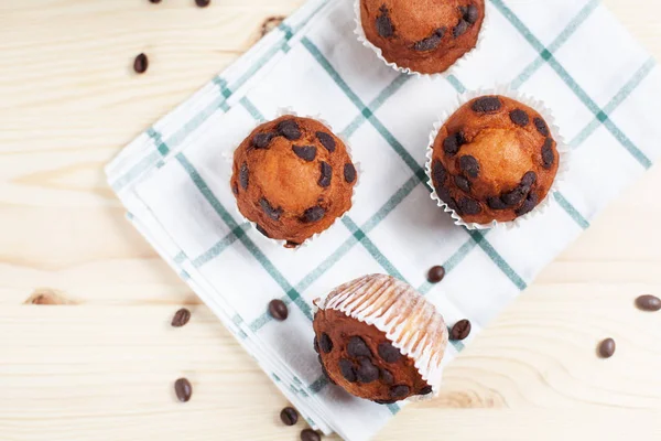 Cupcake al cioccolato su un piattino bianco su un asciugamano verde su uno sfondo di legno chiaro — Foto Stock