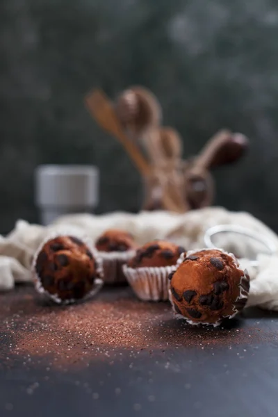 Cupcake al cioccolato, cosparsi di cacao e zucchero con un asciugamano su uno sfondo di legno scuro — Foto Stock