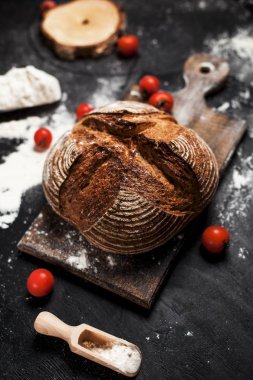 Fırından yeni çıkmış ekmek, un ve bir ahşap tahta bir tablo üzerinde domates