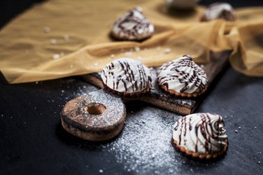 küçük çikolatalı kek çikolata tepesi ile serpilir farklı içler ile karanlık bir arka plan üzerinde altın peçeteye ahşap bir gemide pudra şekeri serpilir