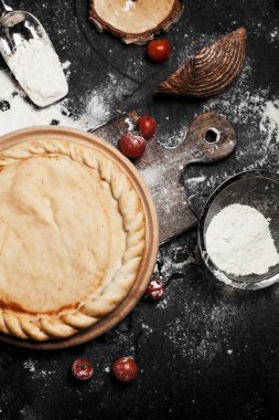 pizza, un ve bir yuvarlak ahşap tahta siyah ahşap bir masa üzerine domates için hazırlık