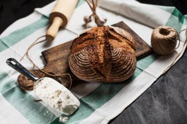 Fırından yeni çıkmış ekmek ve un ahşap oyun tahtası üzerinde bir tablo üzerinde bir mutfak havlusu