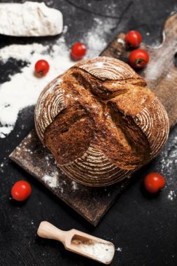 Fırından yeni çıkmış ekmek, un ve bir ahşap tahta bir tablo üzerinde domates