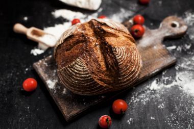 Fırından yeni çıkmış ekmek, un ve bir ahşap tahta bir tablo üzerinde domates