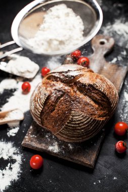 Fırından yeni çıkmış ekmek, un ve bir ahşap tahta bir tablo üzerinde domates