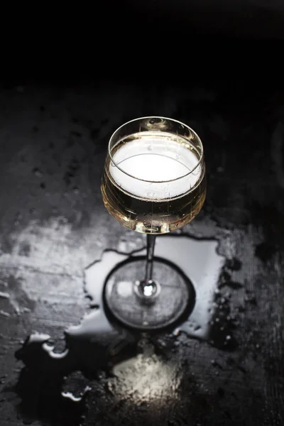 misted glass with champagne on a black, wooden background