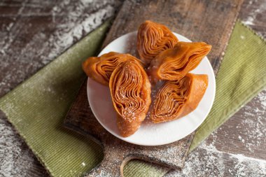 Beyaz tabakta yılbaşı masada şenlikli tatlılar yeşil peçete ve yılbaşı ışıkları karanlık bir arka plan üzerinde