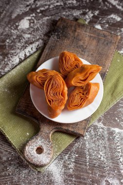 Beyaz tabakta yılbaşı masada şenlikli tatlılar yeşil peçete ve yılbaşı ışıkları karanlık bir arka plan üzerinde