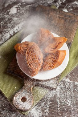 Beyaz tabakta yılbaşı masada şenlikli tatlılar yeşil peçete ve yılbaşı ışıkları karanlık bir arka plan üzerinde