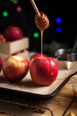 Yılbaşı tatil, yılbaşı ağacı ve yılbaşı ışıkları, bal ve tarçın karanlık bir arka plan üzerinde ahşap kesme tahtası için pişmiş elma yemek