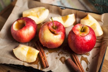 Yılbaşı tatil, yılbaşı ağacı ve yılbaşı ışıkları, bal ve tarçın karanlık bir arka plan üzerinde ahşap kesme tahtası için pişmiş elma yemek