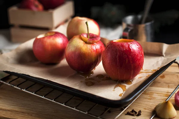 Cuisson de pommes cuites au four pour les fêtes du Nouvel An, sapin de Noël et lumières du Nouvel An, miel et cannelle sur une planche à découper en bois sur un fond sombre — Photo