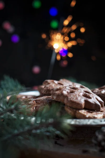 Μελόψωμο cookies για το νέο έτος σε ένα ασημένιο δίσκο, Πρωτοχρονιά φώτα, πυροτεχνήματα, ελάτων, κώνοι, κανέλα σε ένα ξύλινο κοπή του σκάφους σε σκούρο φόντο — Φωτογραφία Αρχείου