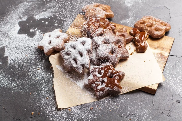 Christmas cookies with powdered sugar on a wooden, cutting board on a gray background