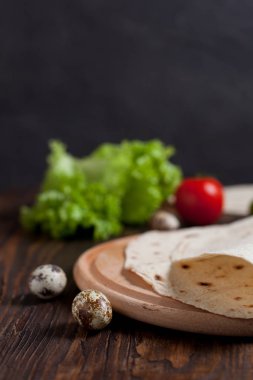 Yeşiller, salatalık, domates ve bir yuvarlak ahşap tahta ahşap arka plan üzerinde üzerinde sosis pişirme börek