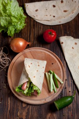 Yeşiller, salatalık, domates ve bir yuvarlak ahşap tahta ahşap arka plan üzerinde üzerinde sosis pişirme börek