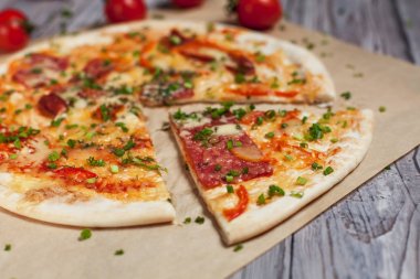 Peynir, pastırma, biber ve hafif ahşap arka plan üzerinde otlar ile ince hamur pizza