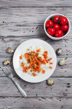 haşlanmış havuç, bezelye ve soğanlı beyaz tabakta, bıldırcın yumurtası ile lezzetli pirinç kase kiraz domates, biber ve ahşap masa lambası çatalı