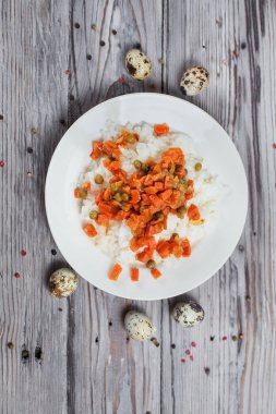 haşlanmış havuç, bezelye ve soğanlı bir beyaz tabak, bıldırcın yumurtası, biber ve ahşap masa lambası çatalı ile lezzetli pirinç