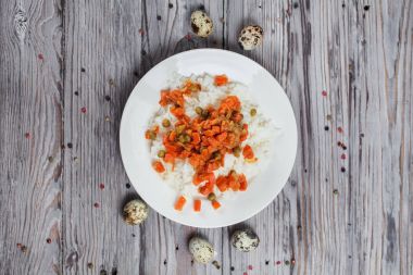 haşlanmış havuç, bezelye ve soğanlı bir beyaz tabak, bıldırcın yumurtası, biber ve ahşap masa lambası çatalı ile lezzetli pirinç