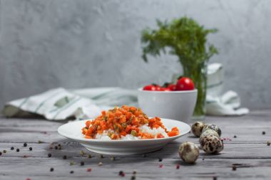 haşlanmış havuç, bezelye ve soğanlı beyaz tabakta, bıldırcın yumurtası ile lezzetli pirinç kase kiraz domates, havlu, biber ve hafif ahşap bir masa üzerine dereotu ile