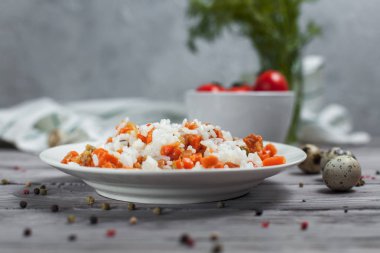 haşlanmış havuç, bezelye ve soğanlı beyaz tabakta, bıldırcın yumurtası ile lezzetli pirinç kase kiraz domates, havlu, biber ve hafif ahşap bir masa üzerine dereotu ile