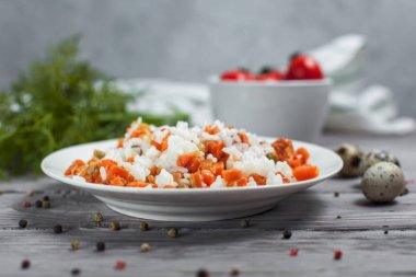 haşlanmış havuç, bezelye ve soğanlı beyaz tabakta, bıldırcın yumurtası ile lezzetli pirinç kase kiraz domates, havlu, biber ve hafif ahşap bir masa üzerine dereotu ile