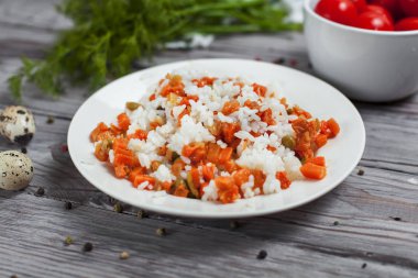 haşlanmış havuç, bezelye ve soğanlı beyaz tabakta, bıldırcın yumurtası ile lezzetli pirinç kase kiraz domates, havlu, biber ve hafif ahşap bir masa üzerine dereotu ile