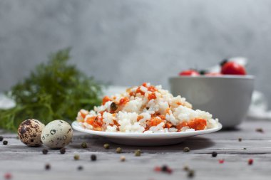 haşlanmış havuç, bezelye ve soğanlı beyaz tabakta, bıldırcın yumurtası ile lezzetli pirinç kase kiraz domates, havlu, biber ve hafif ahşap bir masa üzerine dereotu ile