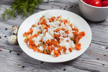 haşlanmış havuç, bezelye ve soğanlı beyaz tabakta, bıldırcın yumurtası ile lezzetli pirinç kase kiraz domates, havlu, biber ve hafif ahşap bir masa üzerine dereotu ile