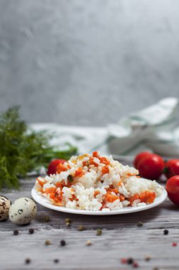 haşlanmış havuç, bezelye ve soğanlı beyaz tabakta, bıldırcın yumurtası ile lezzetli pirinç kase kiraz domates, havlu, biber ve hafif ahşap bir masa üzerine dereotu ile