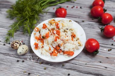 haşlanmış havuç, bezelye ve soğanlı beyaz tabakta, bıldırcın yumurtası ile lezzetli pirinç kase kiraz domates, havlu, biber ve hafif ahşap bir masa üzerine dereotu ile