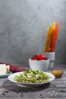 ham spagetti, peynir, dereotu ve kiraz domates hafif ahşap bir masa üzerinde bir kase ile tabak makarna ıspanak ve mozzarella peyniri ve beyaz bir plaka, Fransız hardalı, yeşillik ile yeşil renkli