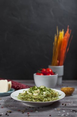 ham spagetti, peynir, dereotu ve kiraz domates hafif ahşap bir masa üzerinde bir kase ile tabak makarna ıspanak ve mozzarella peyniri ve beyaz bir plaka, Fransız hardalı, yeşillik ile yeşil renkli