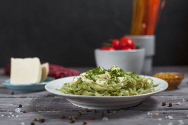 ham spagetti, peynir, dereotu ve kiraz domates hafif ahşap bir masa üzerinde bir kase ile tabak makarna ıspanak ve mozzarella peyniri ve beyaz bir plaka, Fransız hardalı, yeşillik ile yeşil renkli