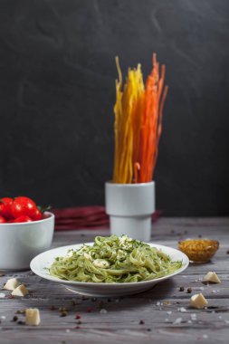 ham spagetti, peynir, dereotu ve kiraz domates hafif ahşap bir masa üzerinde bir kase ile tabak makarna ıspanak ve mozzarella peyniri ve beyaz bir plaka, Fransız hardalı, yeşillik ile yeşil renkli