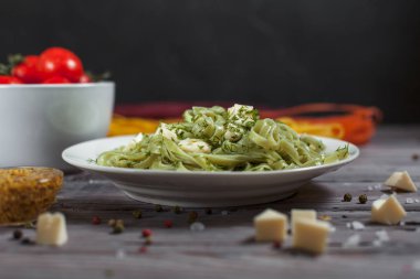 ham spagetti, peynir, dereotu ve kiraz domates hafif ahşap bir masa üzerinde bir kase ile tabak makarna ıspanak ve mozzarella peyniri ve beyaz bir plaka, Fransız hardalı, yeşillik ile yeşil renkli