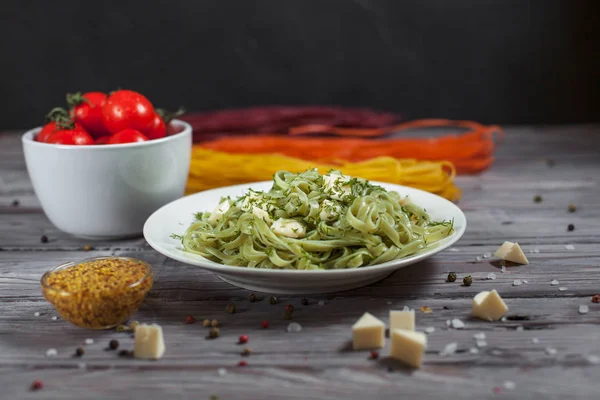 ham spagetti, peynir, dereotu ve kiraz domates hafif ahşap bir masa üzerinde bir kase ile tabak makarna ıspanak ve mozzarella peyniri ve beyaz bir plaka, Fransız hardalı, yeşillik ile yeşil renkli