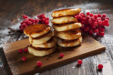 şuruplar ahşap kesme tahtası, bir kartopu Berry bir elek pudra şekeri ve koyu ahşap bir masa üzerine karamel tepesi ile