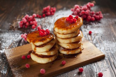 şuruplar ahşap kesme tahtası, bir kartopu Berry bir elek pudra şekeri ve koyu ahşap bir masa üzerine karamel tepesi ile
