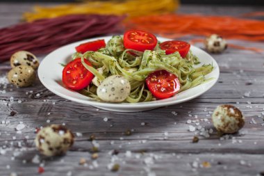 Mozzarella peyniri, yeşillik ve Fransız hardalı, bıldırcın yumurtası ve kiraz domates bir plaka, biber ve karanlık bir arka plan üzerinde gri bir ahşap masa üzerinde büyük deniz tuzu ile yeşil ıspanaklı makarna